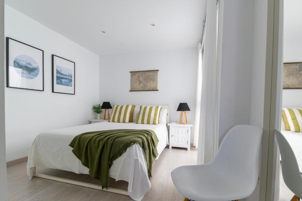 une chambre blanche avec un lit et une chaise dans l'établissement Amplio apartamento recién reformado, à Playa de Arguineguín