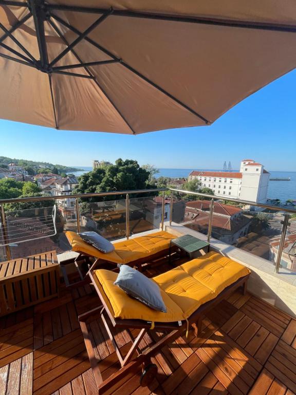 a balcony with yellow chairs and an umbrella at Petar Aparts in Balchik