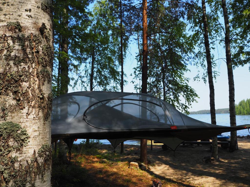 uma tenda sentada num suporte ao lado de uma árvore em LevonMajat em Joensuu