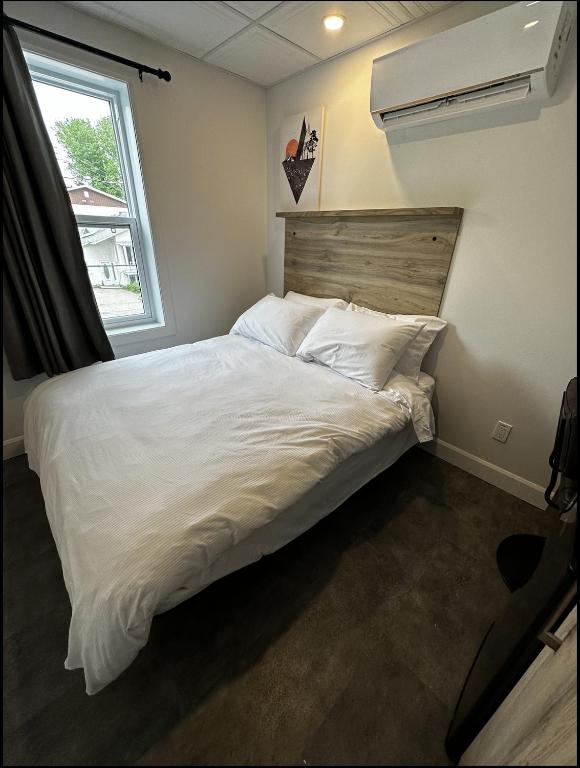 Un dormitorio con una gran cama blanca y una ventana en Le Chambreur, en Rouyn