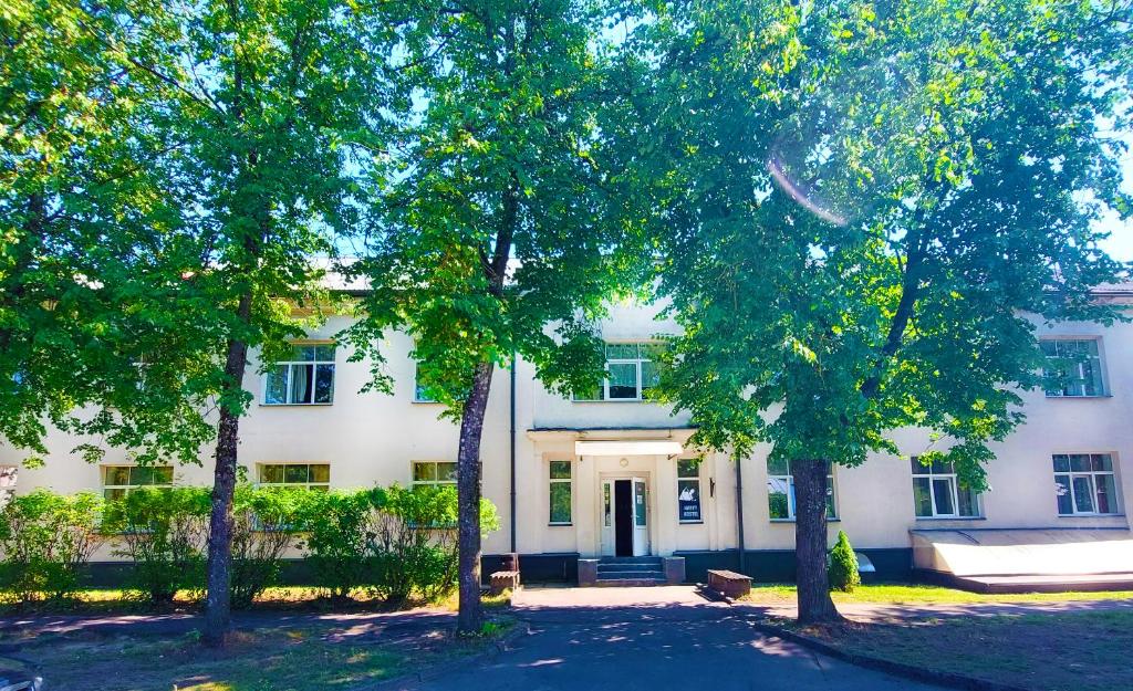 une maison blanche avec des arbres devant elle dans l'établissement Happy Hostel, à Riga