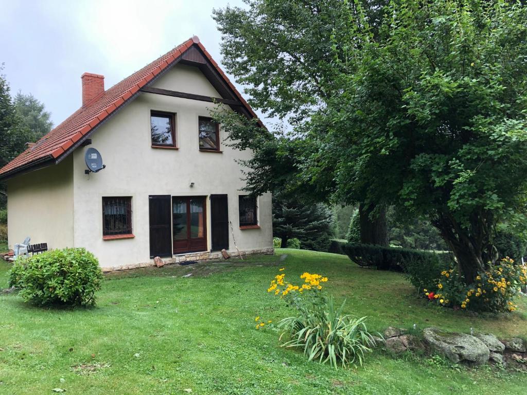 a white house with a yard with flowers at Dom w Rzeczce Góry Sowie in Rzeczka