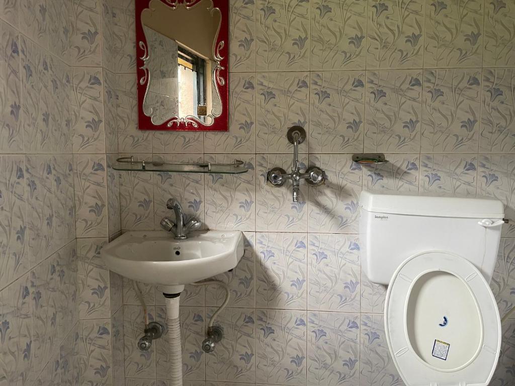 un bagno con un water, un lavandino e uno specchio di Yuriko Guest House a Pokhara