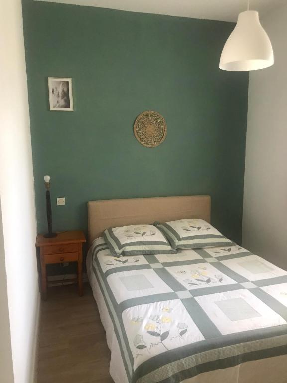 - une chambre dotée d'un lit avec un mur vert dans l'établissement Karinou, à Eaux-Bonnes