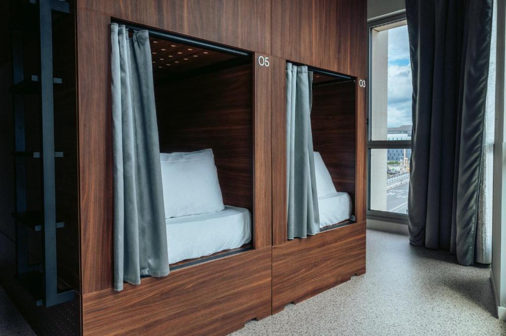 a room with a glass partition with a bed in it at JOST Hostel Bordeaux Gare St Jean in Bordeaux