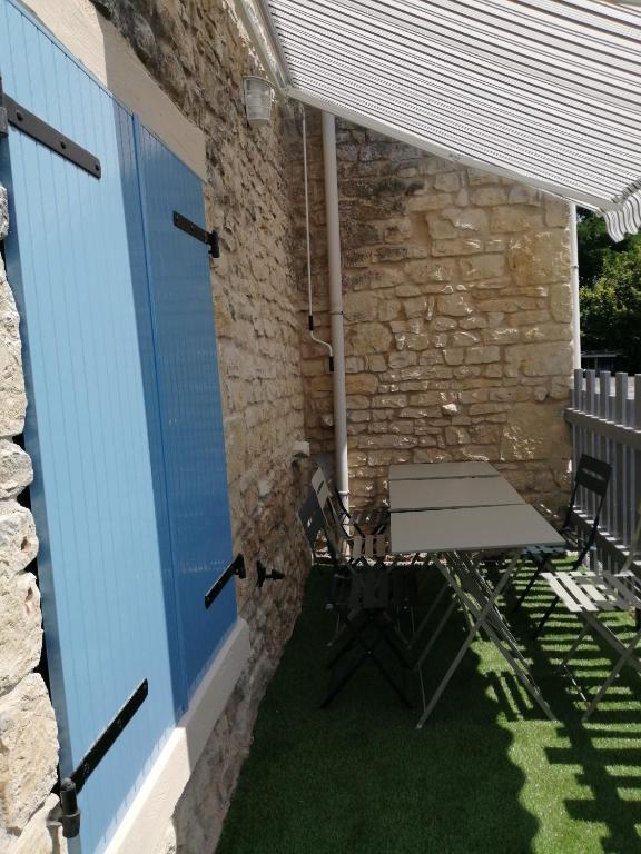 a table and chairs under awning on a patio at Gite Bin Benaise sans linge in Pamproux