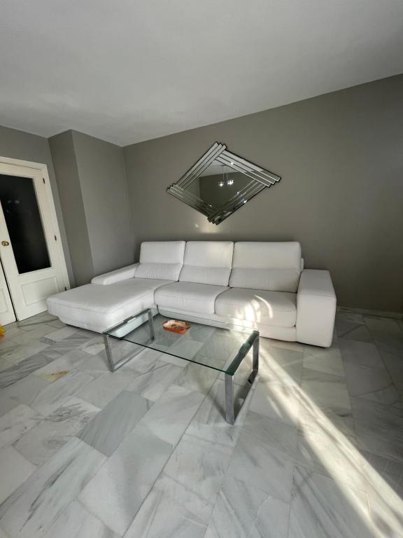 un soggiorno con divano bianco e tavolo in vetro di Apartamento Jardines del Rocío a Torre del Mar