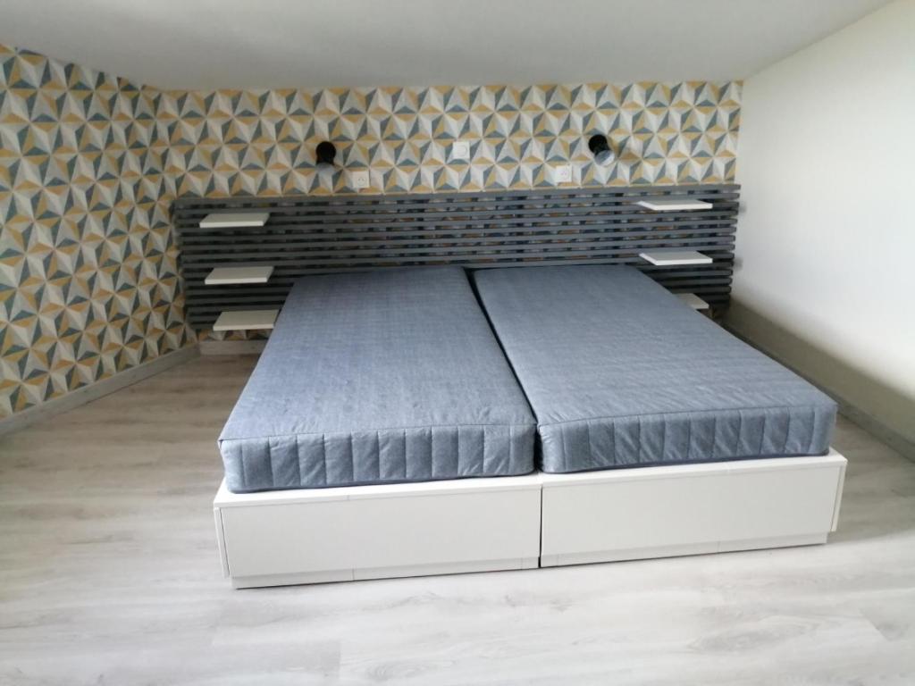 a large bed in a room with a wall at Gite Bin Benaise sans linge in Pamproux
