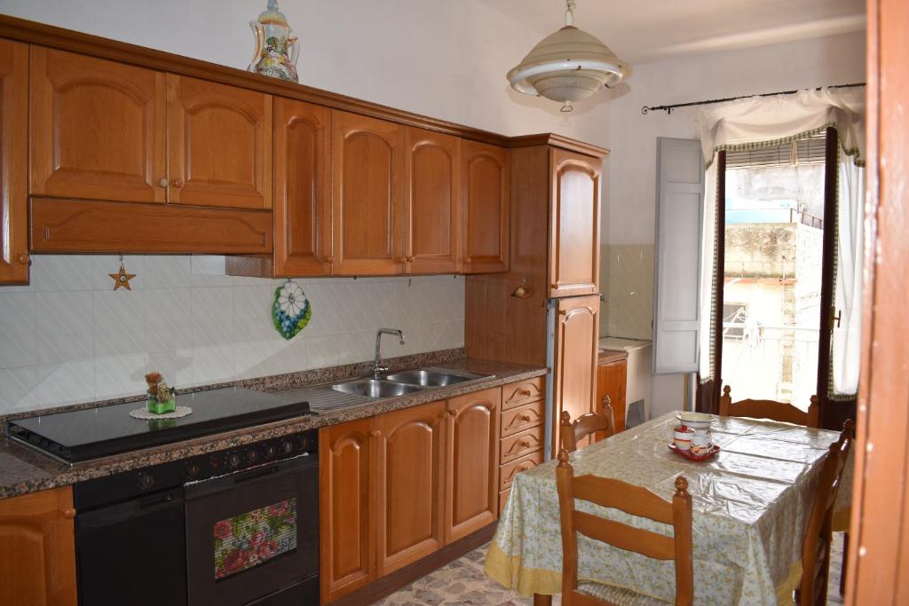 una cucina con armadi in legno, lavandino e tavolo di Appartamento ammobiliato a Pietraperzia