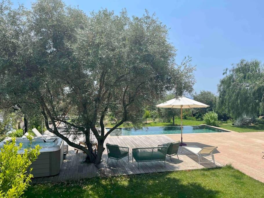 un patio avec des chaises et un parasol à côté d'une piscine dans l'établissement Villa Masa au calme vue colline et aperçu sur la mer, aux Lecques