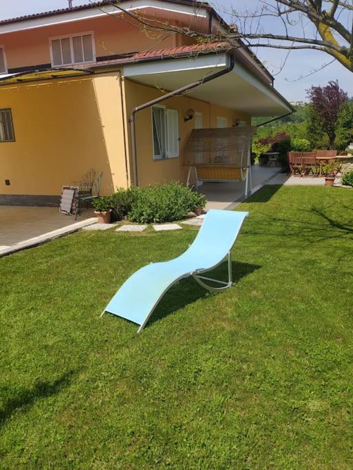 a white chair sitting in the grass in front of a house at Taoretto 1 in Serravalle delle Langhe