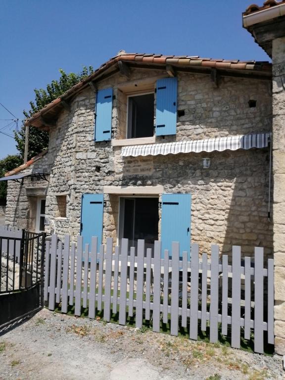 a white picket fence in front of a stone house at Gite Bin Benaise sans linge in Pamproux