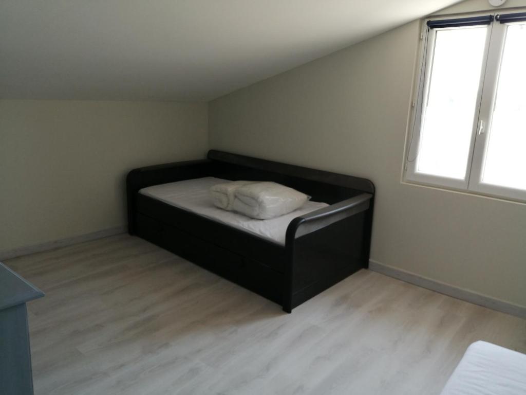a black bed in a room with a window at Gite Bin Benaise sans linge in Pamproux