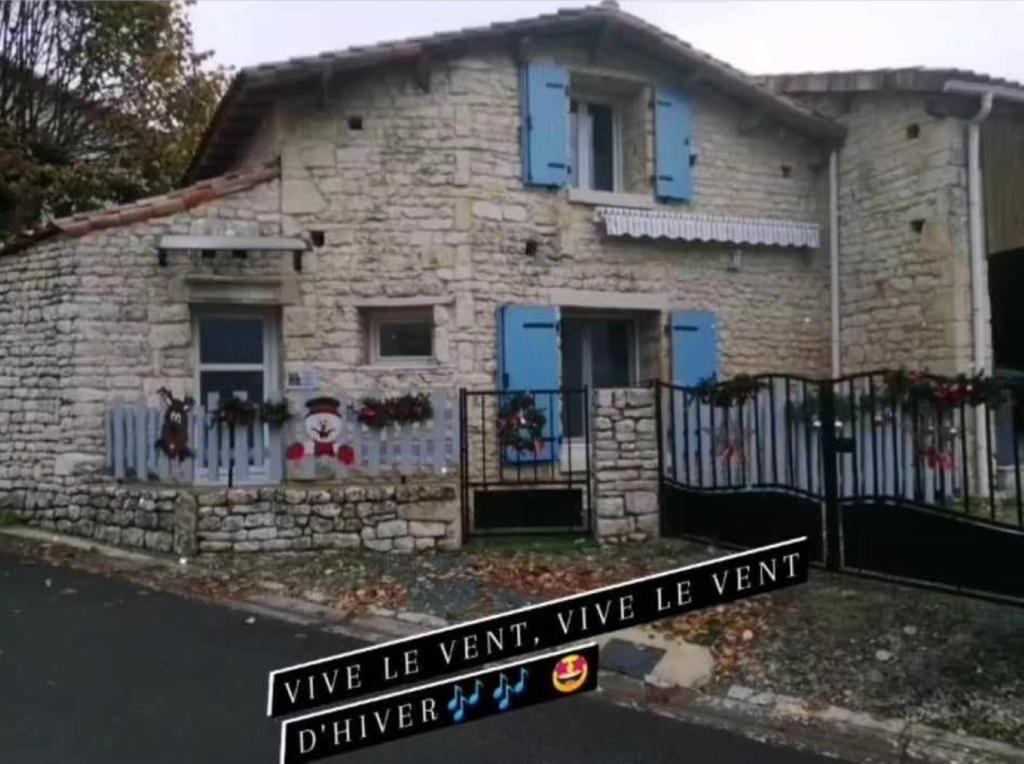 a stone house with blue doors and a fence at Gite Bin Benaise sans linge in Pamproux