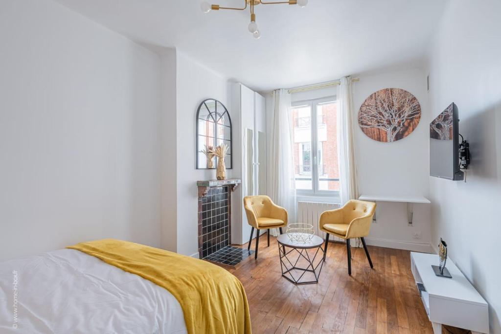 une chambre avec un lit et deux chaises dans l'établissement Logement de standing à 18min de Paris La Défense, à Colombes