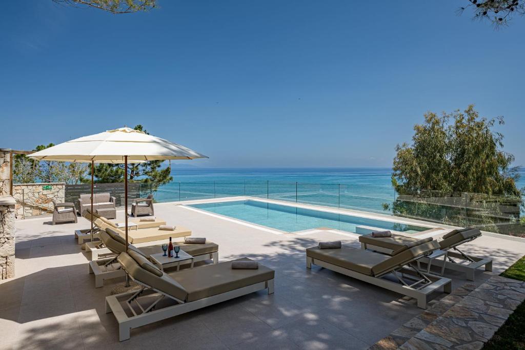 a swimming pool with lounge chairs and an umbrella at Addimare Sea View Villa, and Events Venue in Alykes