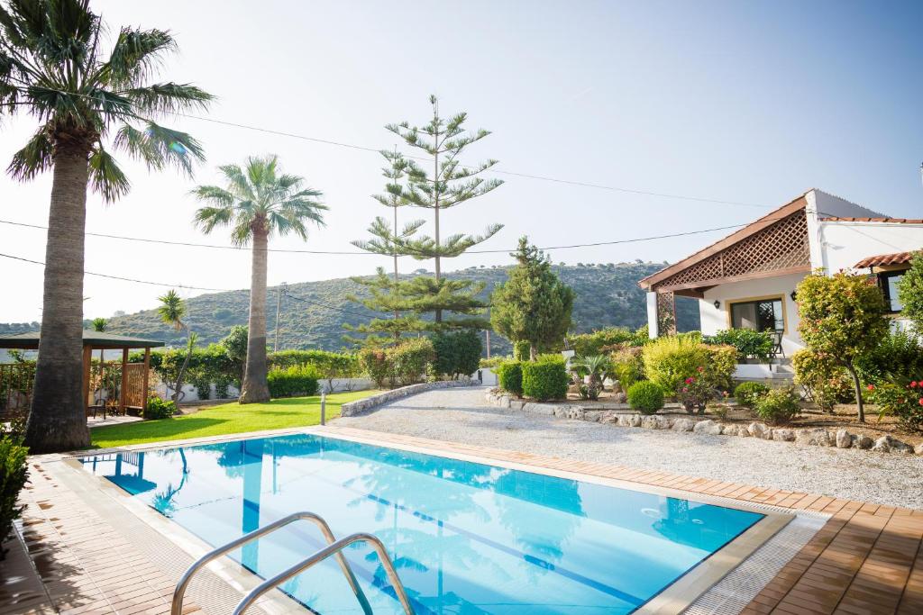 a swimming pool with palm trees and a house at Villa Metochi in Rethymno Town