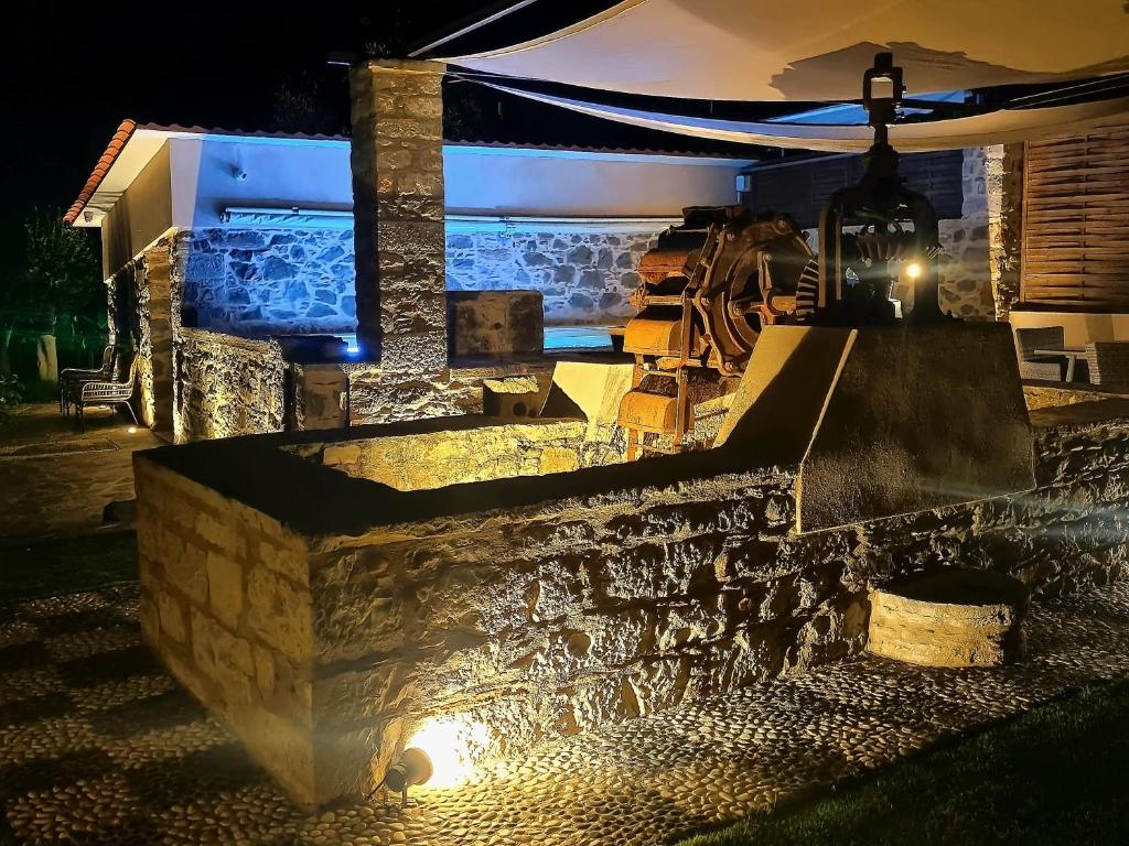 a stone wall with a lit up patio at night at Περιβόλι του Οδυσσέα in Volissos