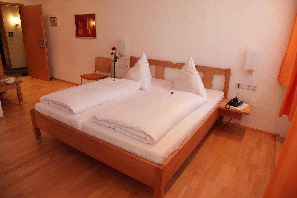 Una cama con sábanas blancas y almohadas. en Gasthof Hotel Bauer en Hersbruck