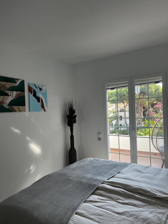 a white bedroom with a bed and a window at Seaside condo with pool, Marbella in Estepona