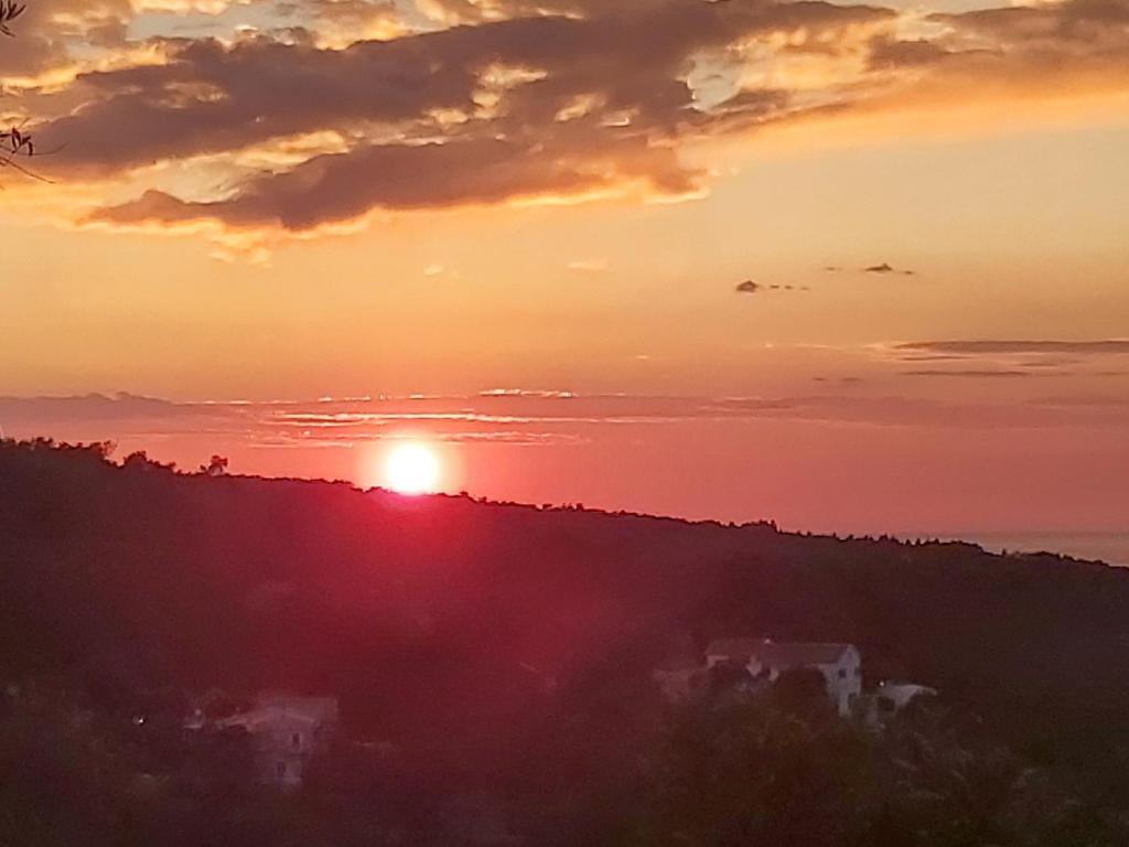 a sunset with the sun setting on a hill at Cosy Studio with breathtaking view in Gaios