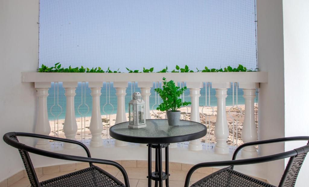 a table with two chairs and a window and a table with a plant at Amazing sea view studio in Ras al Khaimah