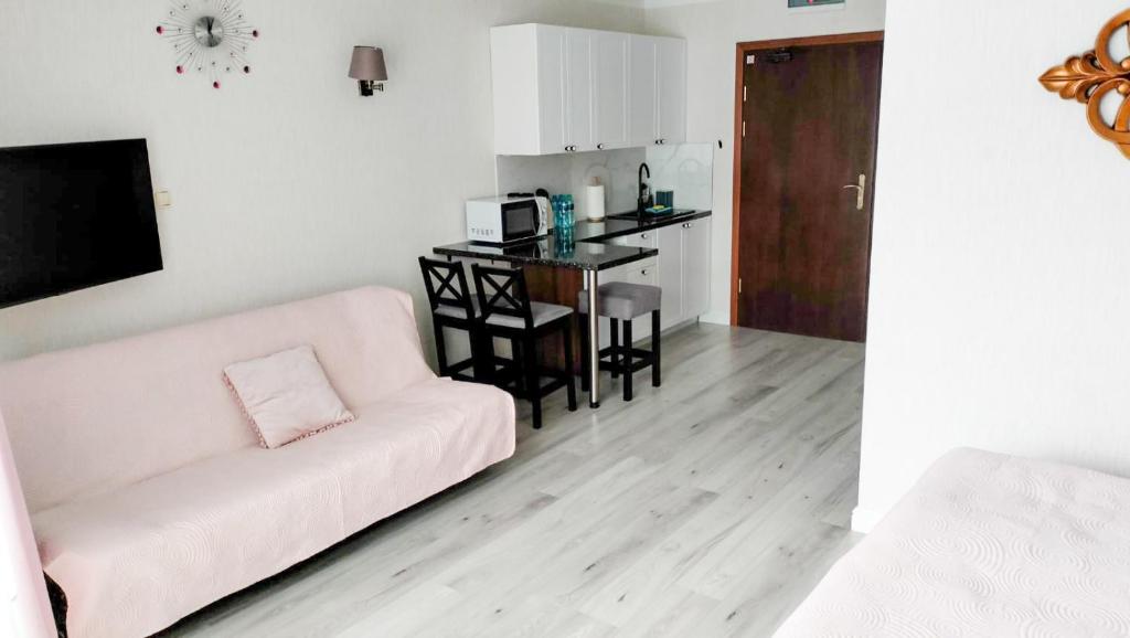 Apartament blisko morza Carmen في كولوبرزيغ: غرفة معيشة مع أريكة بيضاء وطاولة