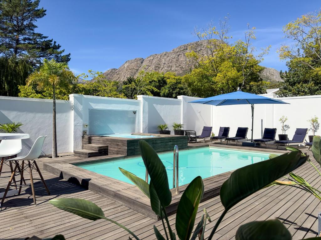 een zwembad met stoelen en een parasol op een terras bij Riebeeck Villa - 5 min walk to Franschhoek Central in Franschhoek