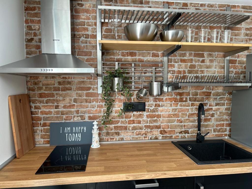 a kitchen with a brick wall and a counter with a sink at Studio Apartments Leut & Lanterna in Vis