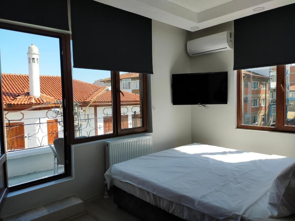 a bedroom with a bed and a tv and windows at Gala Otel Edirne in Edirne