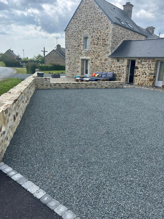 a gravel driveway in front of a stone house at Les Ecuries in Saint-Maurice-en-Cotentin