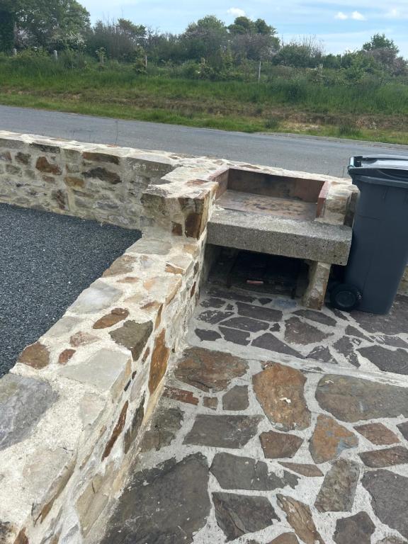 a stone bench sitting next to a trash can at Les Ecuries in Saint-Maurice-en-Cotentin