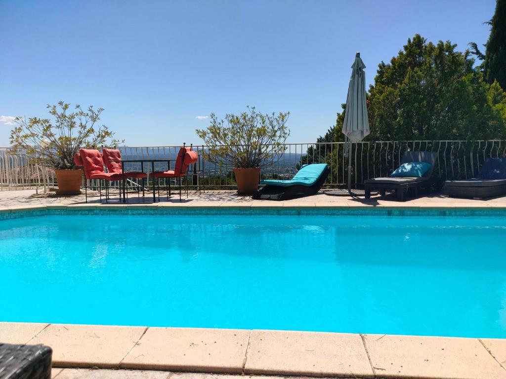 a blue swimming pool with chairs and an umbrella at T2 de la Bastide Rouge vue exceptionnelle (180°) sur Aix domaine privé T2 indépendant de 37 m2 avec terrasse exposée plein sud Piscine 10 X 5 in Aix-en-Provence