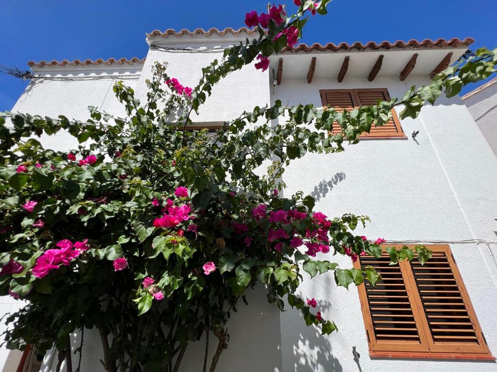 ein weißes Gebäude mit rosa Blumen drauf in der Unterkunft El Xalet d’en Joan Maria d’Altafulla in Altafulla