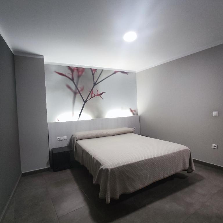 a bedroom with a bed with a painting on the wall at Aparthotel Meseguer in Alcañiz