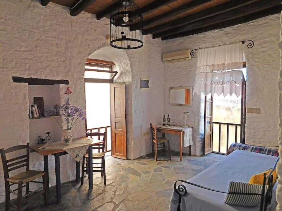 1 dormitorio con 1 cama, mesa y sillas en Philoxeno Traditional house - Ano Syros, en Ano Syros
