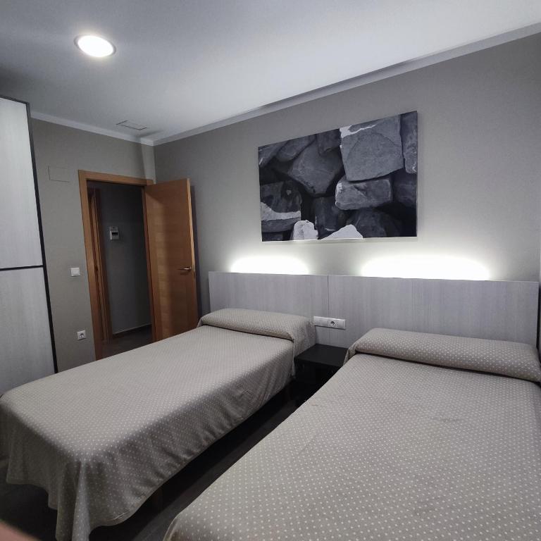 a room with two beds and a painting on the wall at Aparthotel Meseguer in Alcañiz