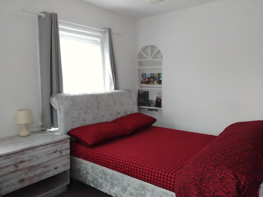 a bedroom with a bed with a red comforter and a window at SOUTH COAST ROOM WITH PARKING SPACE NEAR THE BEACh in Poole