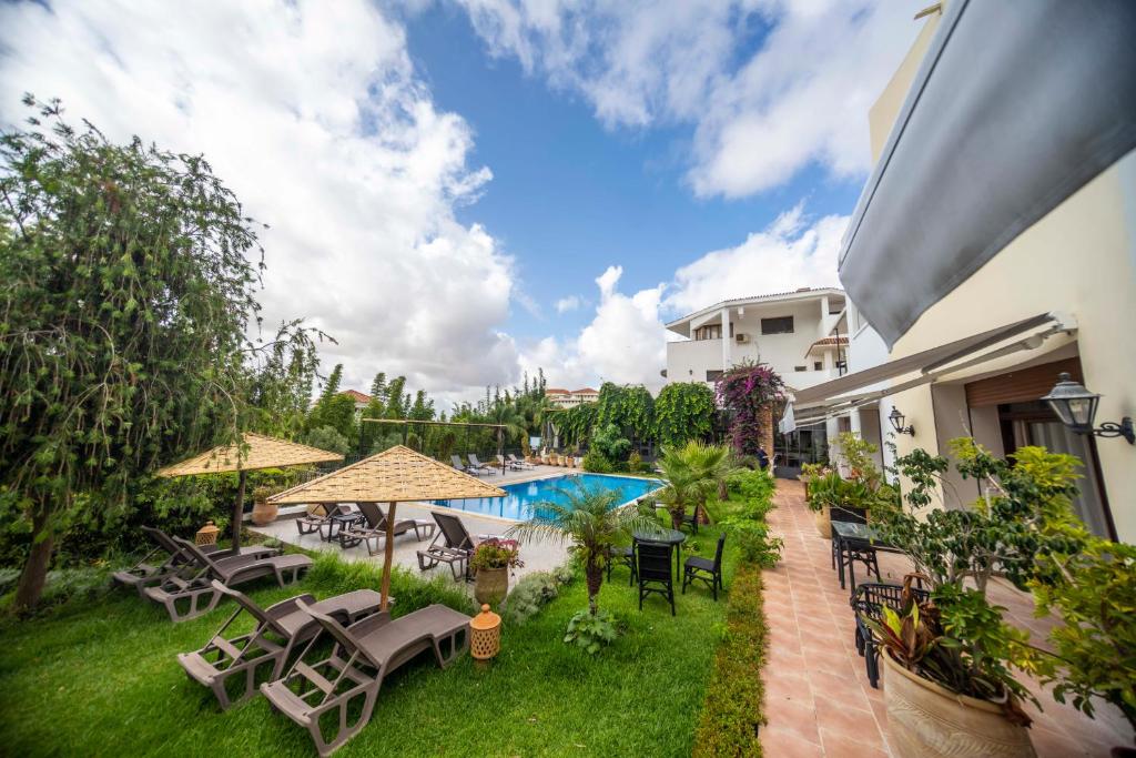 an outdoor patio with tables and chairs and a swimming pool at Dar Tanja Boutique Hotel in Tangier