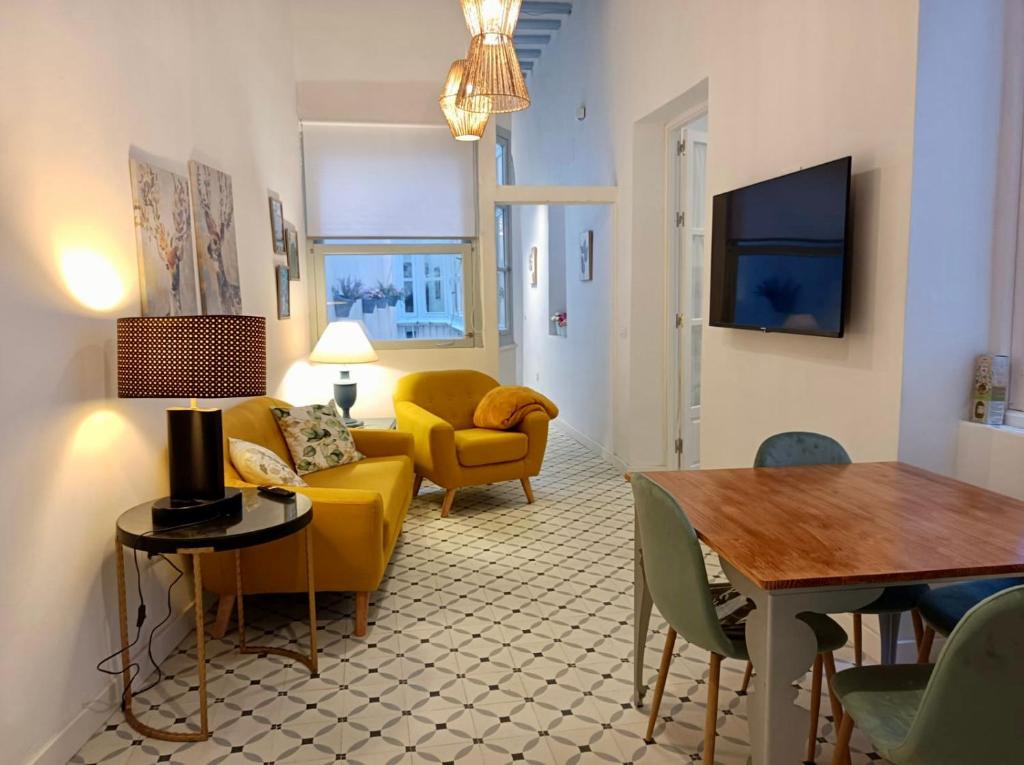 a living room with a yellow couch and a table at Precioso Apartamento: La Luz de Cádiz in Cádiz