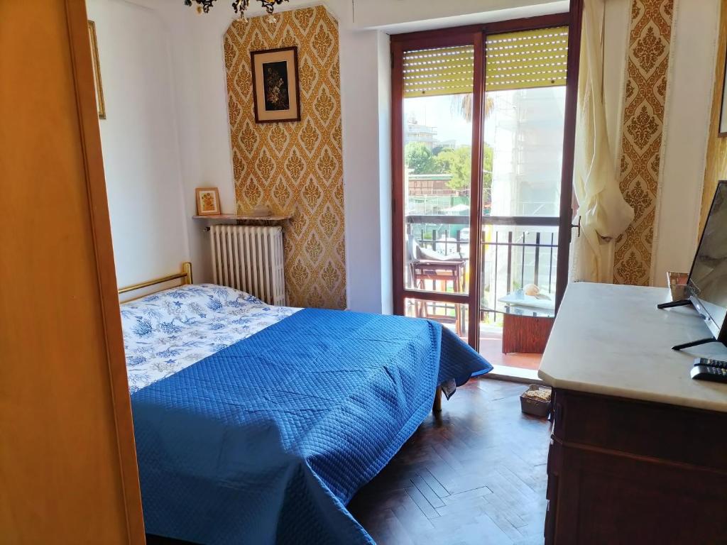 1 dormitorio con cama azul y balcón en La Mouette, en Porto San Giorgio