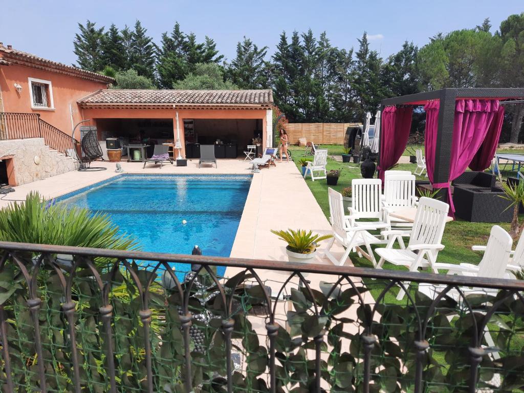 a backyard with a swimming pool and white chairs at Le petit ribbas in Le Cannet-des-Maures