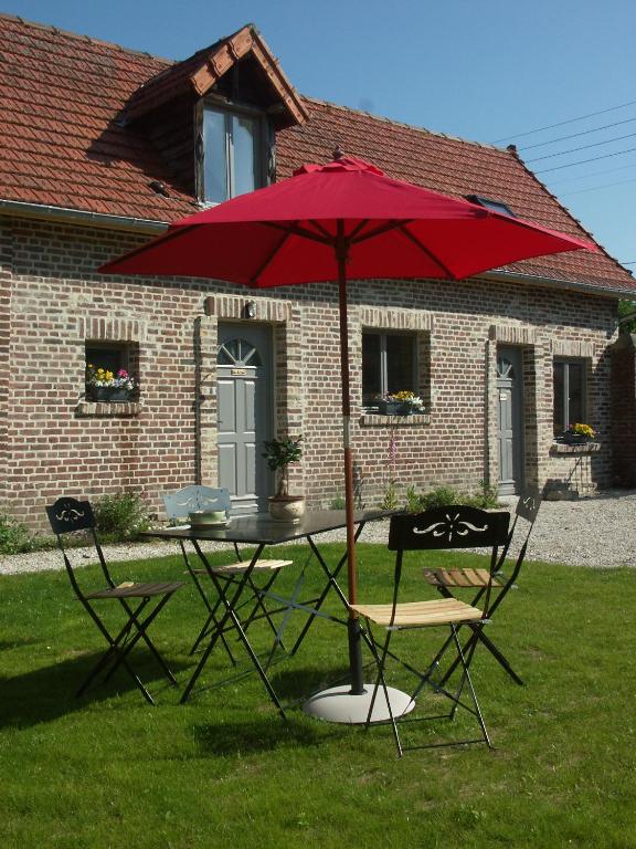 une table et des chaises avec un parasol rouge dans l'herbe dans l'établissement l antre pot, à Arques-la-Bataille