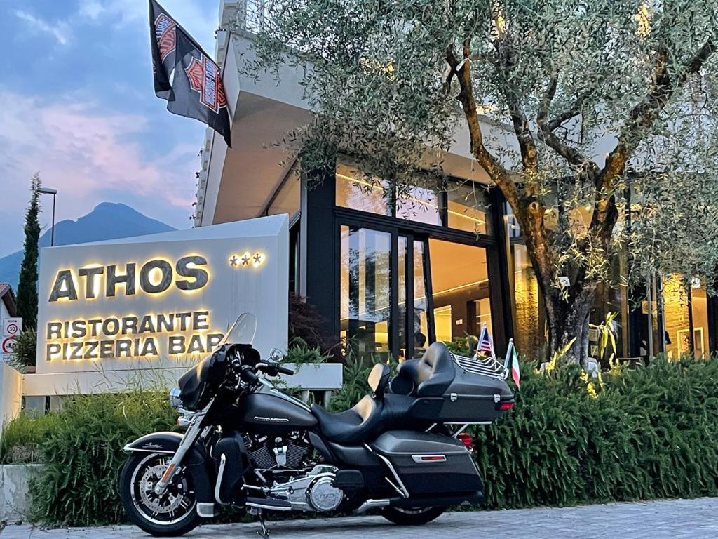 une moto garée devant une pizzeria dans l'établissement Athos Hotel, à Riva del Garda