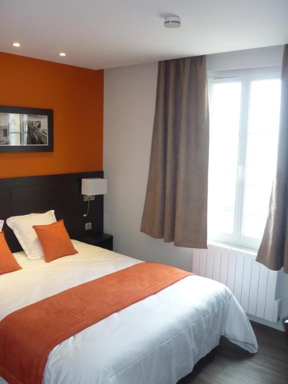 a bedroom with a large bed and a window at Hotel De La Plage in Quiberville
