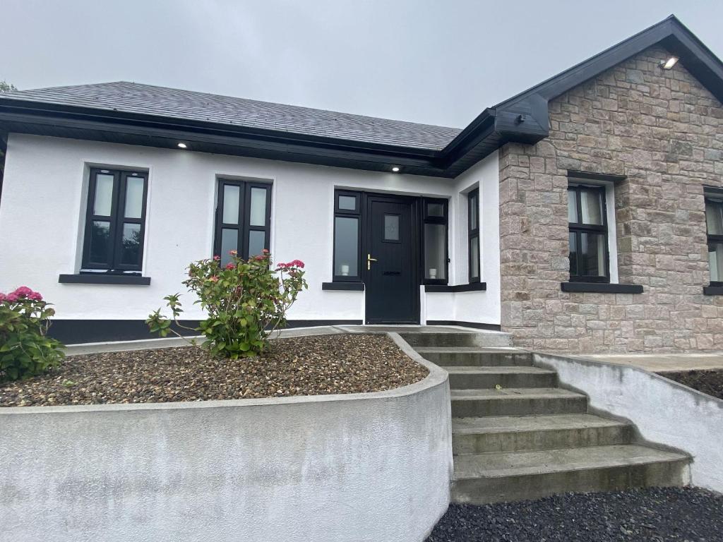 a white house with a black door and stairs at Cottage 442 - Oughterard in Oughterard