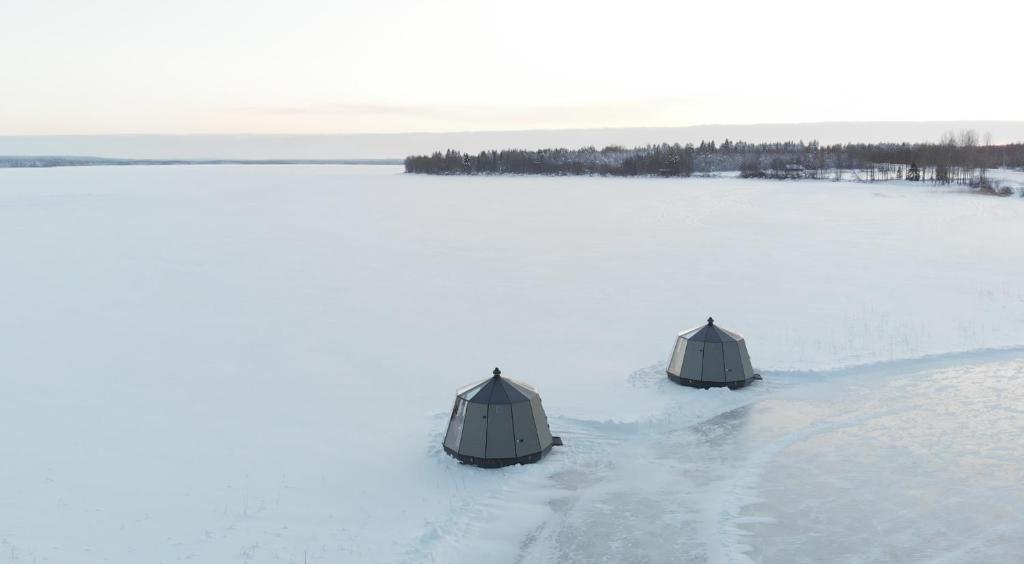 twee koepels in de sneeuw op een sneeuwveld bij Vikajärvi Lake View Experience Igloos in Rovaniemi