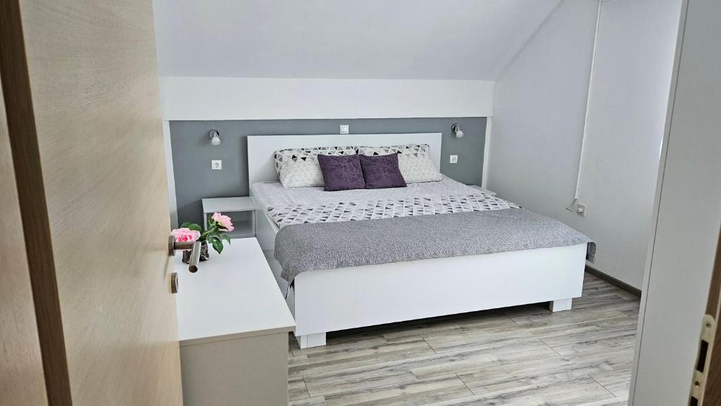 a bedroom with a white bed with purple pillows at Apartment Andrea in Smoljanac