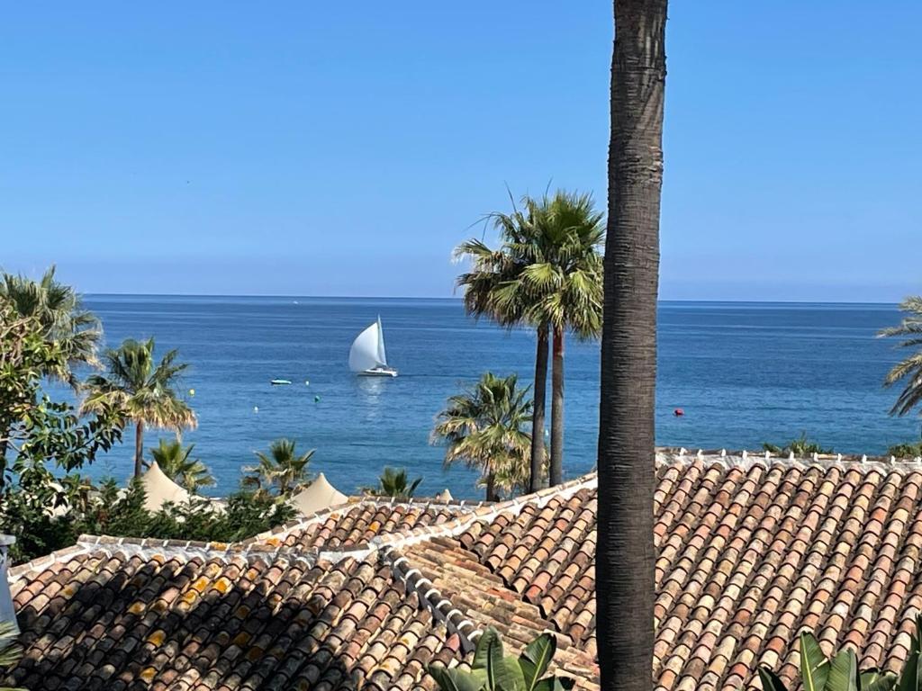 a sail boat in the ocean with palm trees at All About Puente Romano Penthouse Suite in Marbella