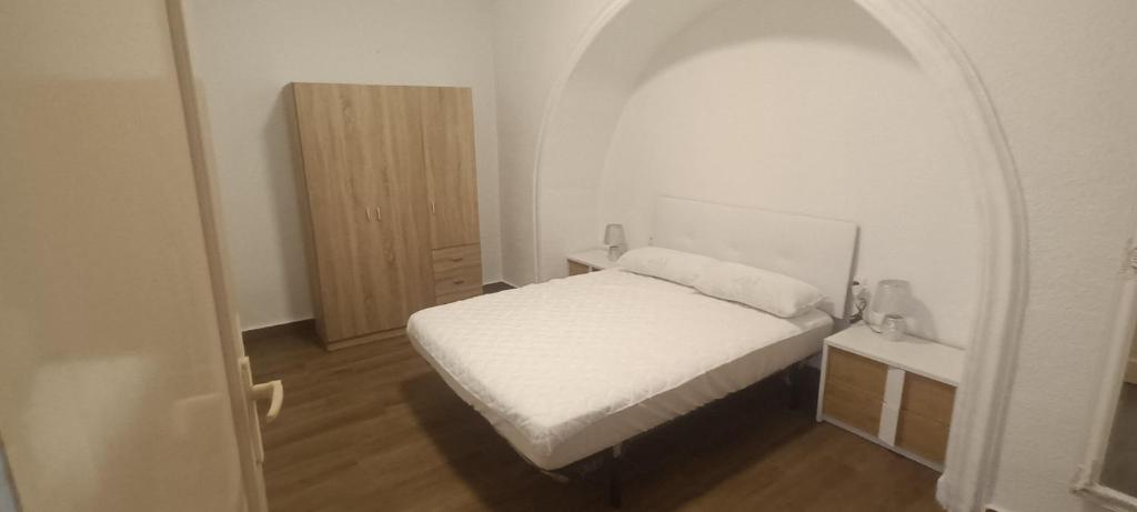 Dormitorio pequeño con cama blanca en un arco en La casita azul, en Torrevieja